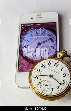 An Antique railroaders pocket watch from 1900 and a modern iPhone from 2011 with an image of the watch in the screen. Stock Photo