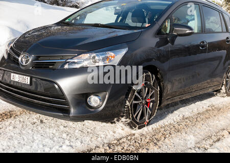 Snow chain / chains on front wheel / wheels of a car also fitted with winter tyres / tires. (75) Stock Photo