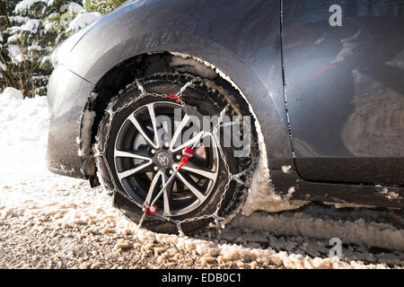 Snow chain / chains on front wheel / wheels of a car also fitted with winter tyres / tires. (75) Stock Photo