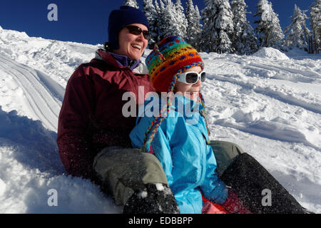 Mother and daughter sledding on snow in mountains, Hurricane Ridge, Clallam County, Olympic National Park, Washington, USA Stock Photo