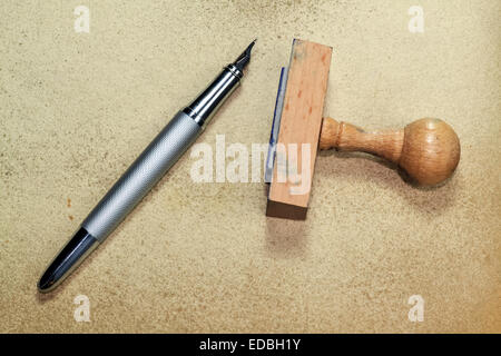Wooden rubber stamp and inky pen on grungy background Stock Photo