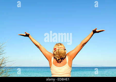 Cheerful woman with arms raised to the sky near the sea Stock Photo