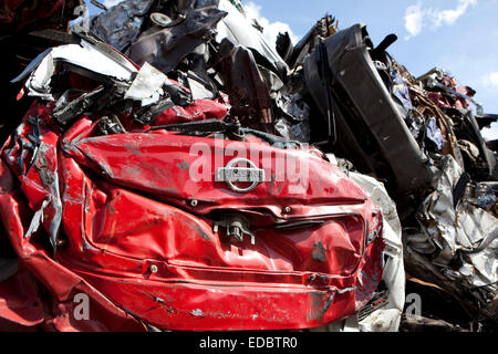 A Nissan car logo is visible amongst a pile of crushed cars. Stock Photo