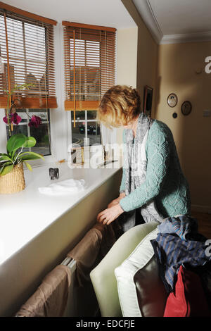 Woman doing chores washing clothes and hanging them to dry on domestic radiator Stock Photo