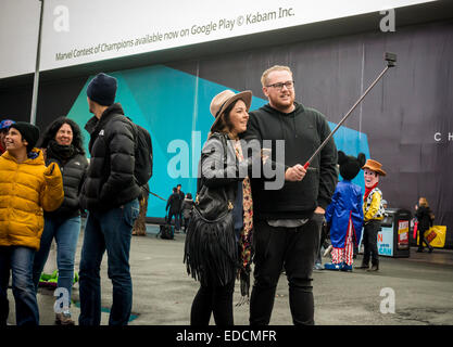 Tourists in Times Square in New York use their selfie sticks to take selfies of themselves and their companions on Sunday, January 4, 2015. The goofy looking accessory was extremely popular this holiday season with many stores having problems keeping them in stock. Estimates are that 100,000 have been sold in the U.S. in December alone and Time magazine christened them the one of the best inventions of the year. (© Richard B. Levine) Stock Photo