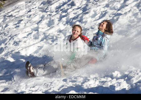 Children sledding down a hill having fun. Lots of action with flying snow an animated faces. Stock Photo