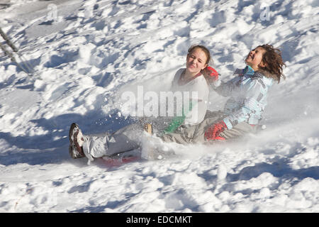 Children sledding down a hill having fun. Lots of action with flying snow an animated faces. Stock Photo