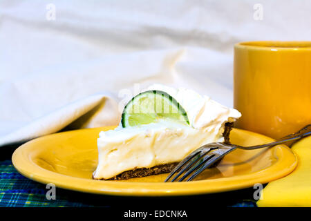 Slice of key lime pie with coffee closeup on plate with fork and napkin. Stock Photo