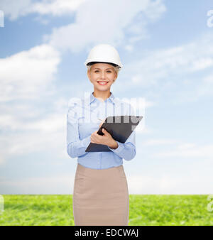 smiling businesswoman in helmet with clipboard Stock Photo