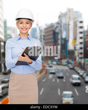 smiling businesswoman in helmet with clipboard Stock Photo