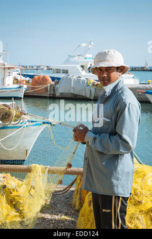 A young fisherman in a harbour repairing his fishing net, Santorini, Cyclades, Greek islands, Greece Stock Photo