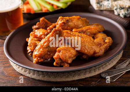 A plate of delicious buffalo style chicken wings with hot sauce, blue cheese, celery sticks, carrot sticks, and beer. Stock Photo