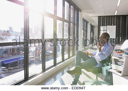 Pensive businessman looking out sunny office window