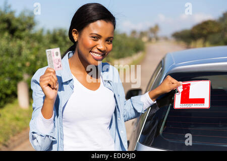 African woman removing learner driver sign after getting her driving license Stock Photo