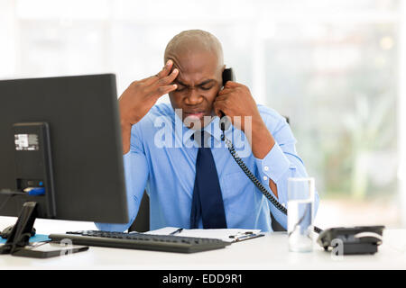 stressed businessman talking on landline phone in modern office Stock Photo