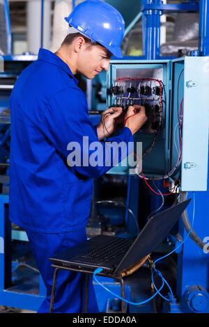 industrial engineer repairing computerized machine with laptop computer Stock Photo