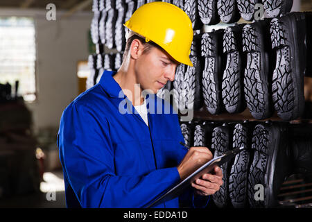 gumboots factory worker checking inventory in stockroom Stock Photo