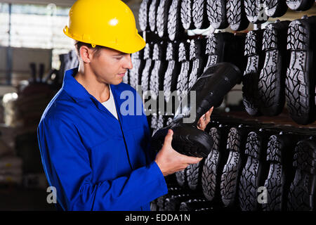 factory worker looking at gumboots in a storeroom Stock Photo