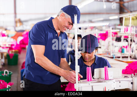 clothing factory quality controller checking stitch on production line Stock Photo
