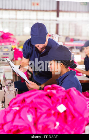 foreman and dressmaker looking at clipboard in factory Stock Photo