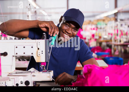 African American mechanic repairing industrial sewing machine in clothing factory Stock Photo