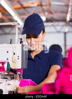pretty female factory worker sewing garment Stock Photo