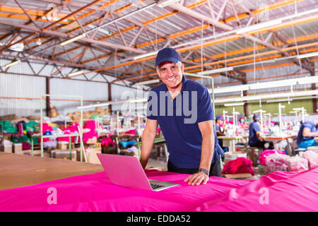 portrait of senior clothing factory manager with laptop computer Stock Photo
