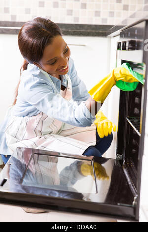 happy African woman cleaning oven in the kitchen Stock Photo