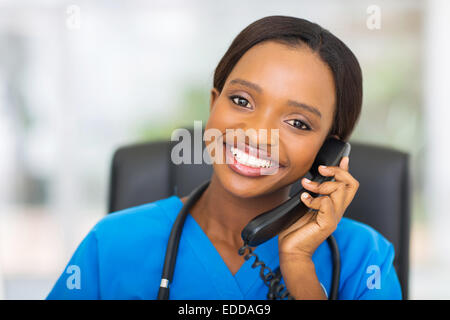 portrait of pretty African American female nurse using landline phone Stock Photo