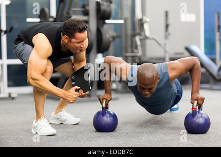 personal trainer motivates client doing push-ups in gym Stock Photo
