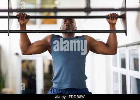 strong African man doing pull-ups on a bar in a gym Stock Photo