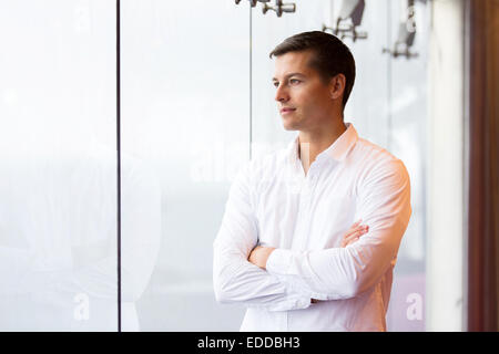thoughtful young man looking outside the window Stock Photo