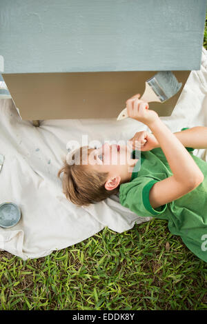 A boy in a garden, painting a dog house. Stock Photo