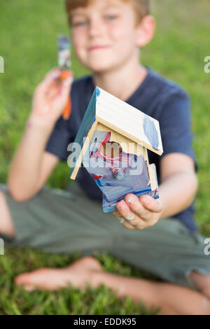 A boy in a garden, painting a bird house. Stock Photo