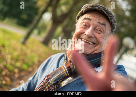 Portrait of happy senior man outdoors doing victory sign Stock Photo