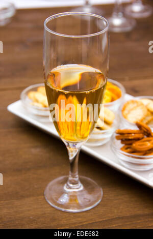 Flute with aperitif and pretzels on wooden table seen close Stock Photo