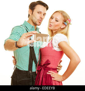 Bavarian couple taking selfie with duckface with a smartphone Stock Photo