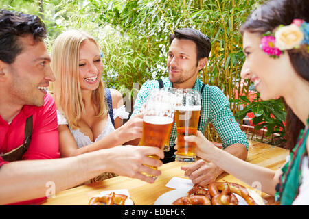 Four happy friends clinking glasses with beer at Oktoberfest Stock Photo