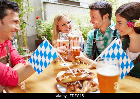 Smiling bavarian friends having fun in beer garden in Germany Stock Photo