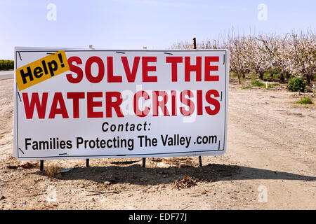 Sign, 'Help!  Solve  The Water Crises'  posted by flowering almond  orchard, Stock Photo