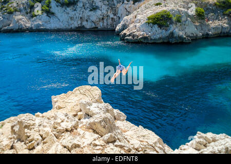 Man diving into beautiful blue water from a rocky outcrop at Calanque de Sugiton Stock Photo