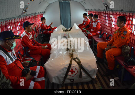 Pangkalan Bun, Indonesia. 6th Jan, 2015. Indonesia red cross sit near coffins of passengers Air Asia QZ 8501 being delivered by Indonesia Air Force aircraft.At this point, 37 bodies of the 162 people who were on board have been recovered. © Jeff Aries/ZUMA Wire/Alamy Live News Stock Photo