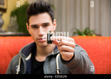 Handsome young man showing USB key in his hand, focus on the electronic drive Stock Photo