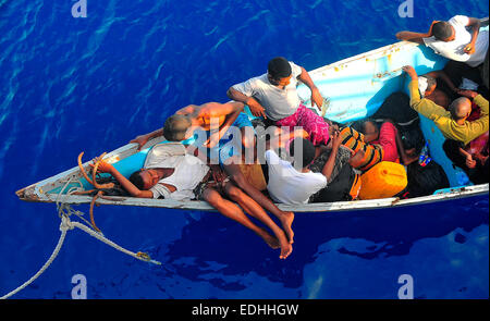 Somali migrants in a disabled skiff wait for assistance from U.S. Navy sailors aboard the guided-missile cruiser USS Lake Champlain May 23, 2009 in the Gulf of Aden. The skiff carrying 52 passengers was spotted in distress by helicopter pilots assigned to the Anti-Submarine Squadron Light 45 while patrolling the area. Stock Photo