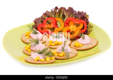 Cream on crackers and vegetables on green plate isolated on white background. Stock Photo