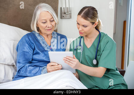 Female Nurse And Senior Woman Using Tablet PC Stock Photo