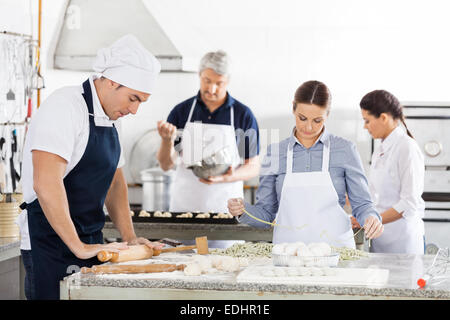 Chefs Making Pasta Together In Kitchen Stock Photo