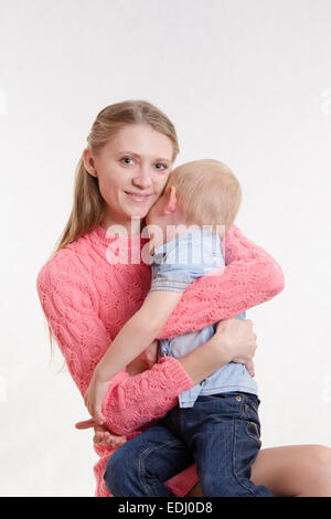 On the lap of a young beautiful girl sits her three year old son Stock Photo