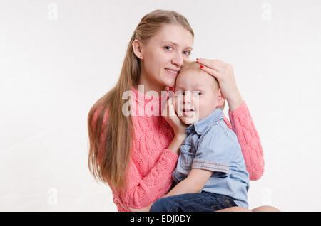 On the lap of a young beautiful girl sits her three year old son Stock Photo