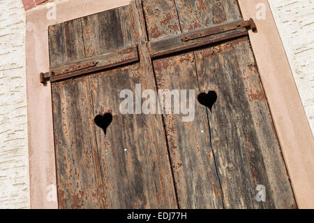 Closed old shuttered weathered wooden window with heart shape in the Alsace, France Stock Photo
